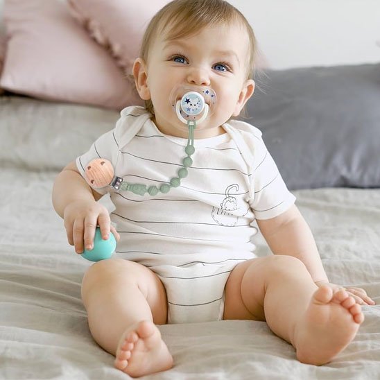 bebe avec Anneau de dentition vert attache a son chandail