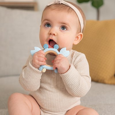 bébé fille met un Anneau de dentition bleu dans sa bouche